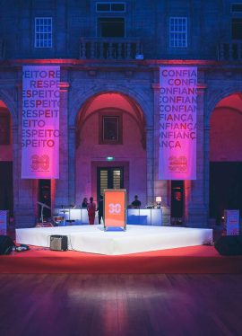 Palco iluminado por luzes roxas e vermelhas em evento de comemoração dos 30 anos de uma marca, organizado pela Rollercoaster Group.